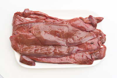Photograph of several raw beef livers piled on a plate