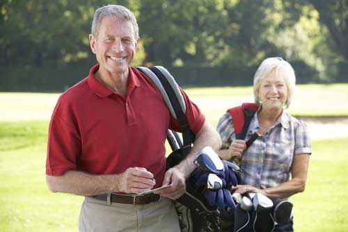 senior couple carrying golf bags