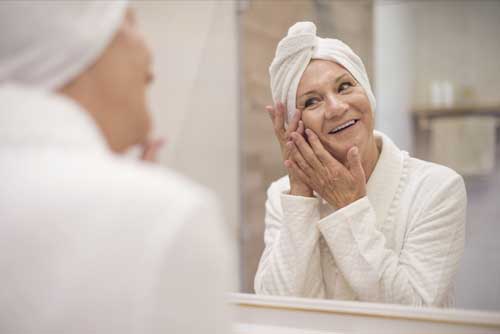 senior woman washing face in the mirror