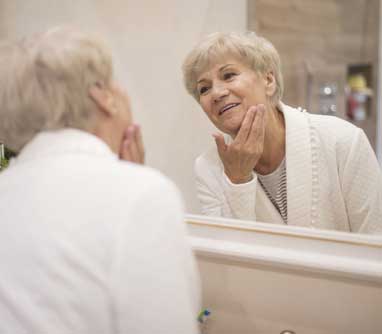 senior woman washing face in the mirror