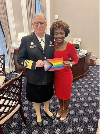 Admiral Rachel Levine with former White house press secretary Karine Jean-Pierre posing side by side and holding a print out of the LGBTQIA+ intersectional flag
