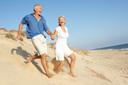 Couple running on the beach, laughing and holding hands